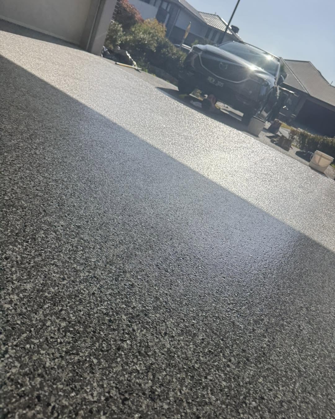 Bound stone epoxy driveway leading up to a modern home